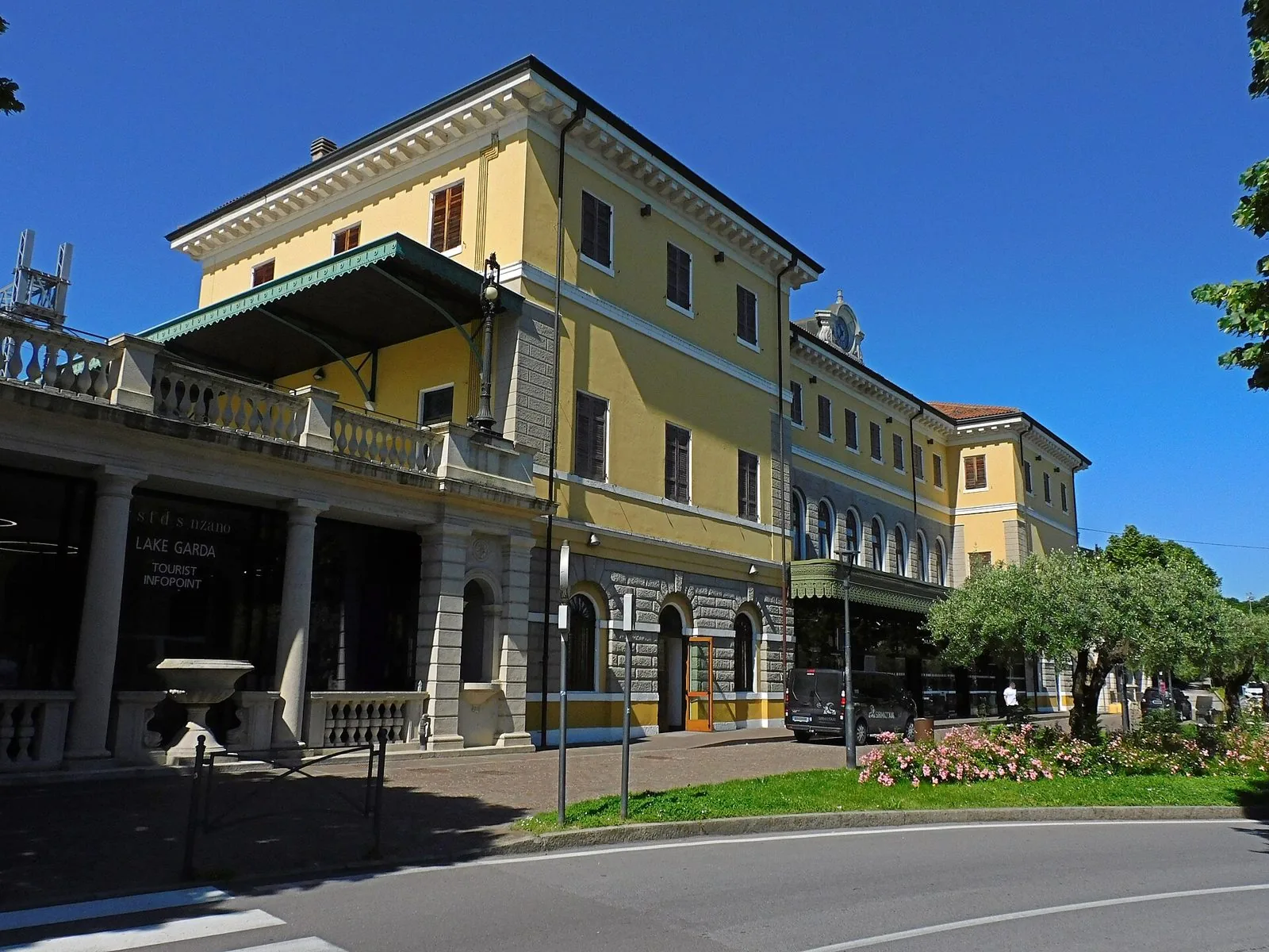 L'edificio giallo della stazione ferroviaria di Desenzano del Garda-Sirmione, con aiuole fiorite davanti
