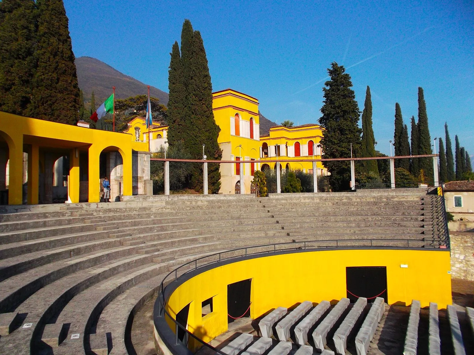 Le gradinate in pietra e il palco giallo dell'anfiteatro del Vittoriale a Gardone Riviera, tra i cipressi